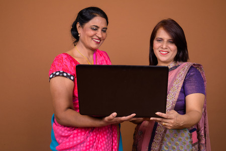Two happy Indian woman using laptop computer togetherの写真素材