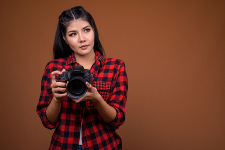 Young beautiful Asian woman photographer thinking and looking upの写真素材