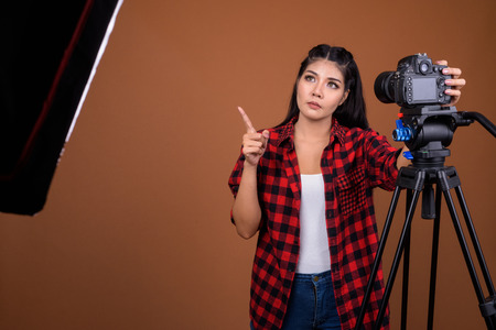 Woman photographer adjusting camera on tripod while thinking