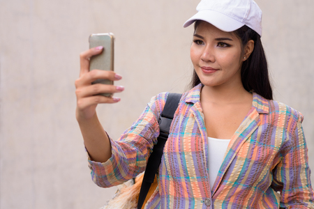 Young beautiful Asian woman using mobile phone outdoorsの写真素材