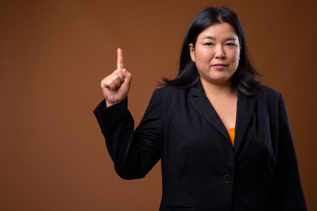 Beautiful overweight Asian businesswoman pointing finger upの写真素材