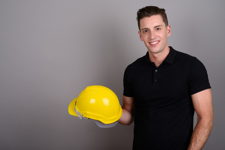 Young handsome man construction worker holding hardhatの写真素材