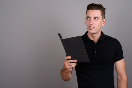 Young handsome man reading book and thinkingの写真素材