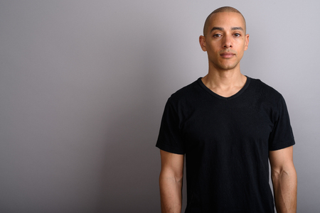 Handsome bald man wearing black shirt against gray backgroundの写真素材