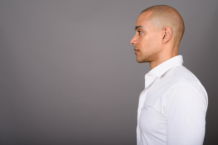 Profile view of handsome bald businessman against gray backgroundの写真素材