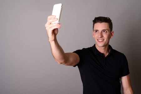 Young handsome man using mobile phone to take selfieの写真素材