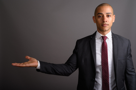 Handsome bald businessman showing copy space against gray backgroundの写真素材