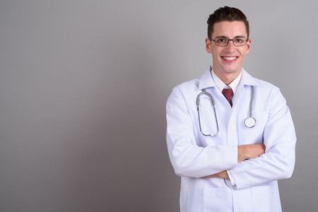 Young handsome man doctor smiling with arms crossedの写真素材