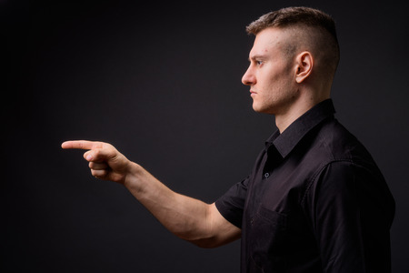 Profile view of young handsome businessman pointing fingerの写真素材