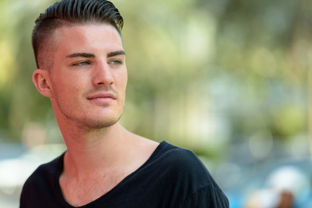 Close up of young handsome man thinking while looking back in th