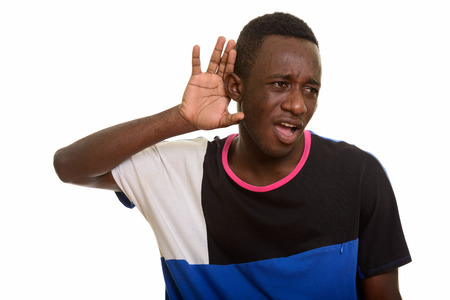 Young African man listening while looking surprised and shockedの写真素材