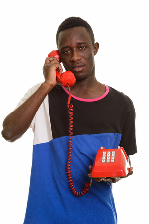 Young African man talking on old telephone looking tiredの写真素材