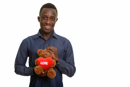 Young happy African man smiling and holding teddy bear with hearの写真素材