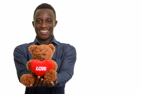 Young happy African man smiling and giving teddy bear with heartの写真素材