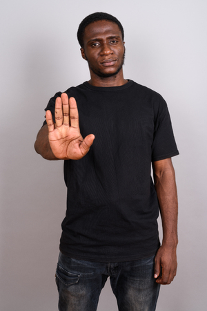 Young African man wearing black shirt against gray backgroundの写真素材