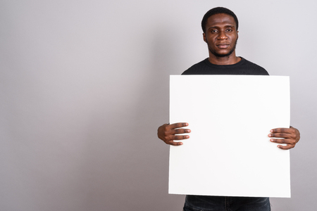 Young African man wearing black shirt against gray backgroundの写真素材