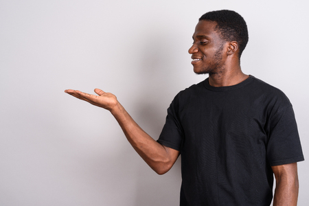 Young African man wearing black shirt against gray backgroundの写真素材