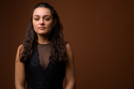 Studio shot of young beautiful woman against brown backgroundの写真素材