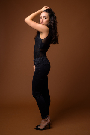 Studio shot of young beautiful woman against brown backgroundの写真素材