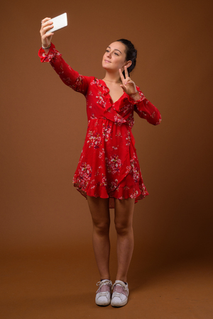 Studio shot of young beautiful woman against brown backgroundの写真素材