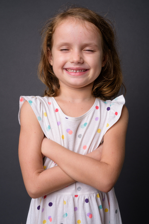 Cute young girl with blond hair against gray backgroundの写真素材