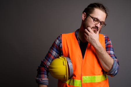 Young bearded man construction worker against gray backgroundの写真素材