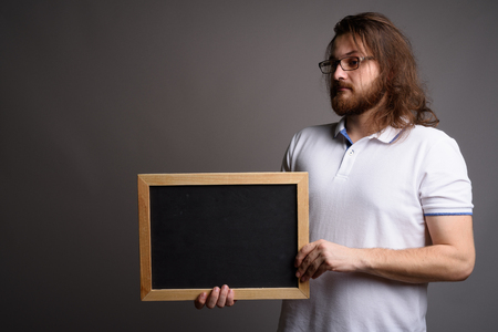 Young bearded man wearing white polo shirt against gray backgrouの写真素材