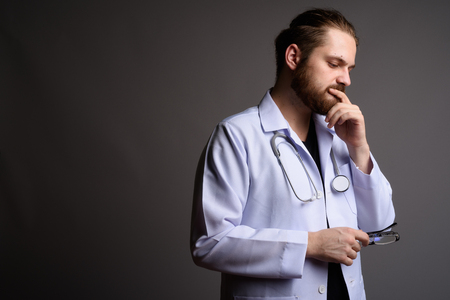 Young bearded man doctor against gray backgroundの写真素材