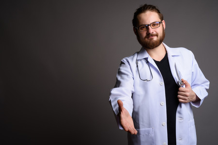 Young bearded man doctor against gray backgroundの写真素材