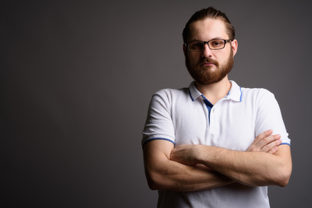 Young bearded man wearing white polo shirt against gray backgrouの写真素材