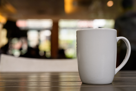 Coffee cup on wooden table in restaurant with defocused background and bokeh effectの写真素材
