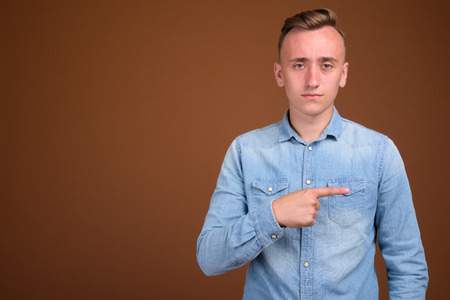 Young handsome man with blond hair against brown backgroundの写真素材