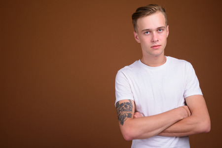 Young handsome man with blond hair against brown backgroundの写真素材