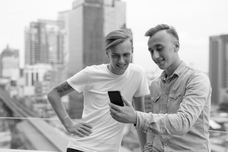 Two young handsome men using mobile phone outdoorsの写真素材