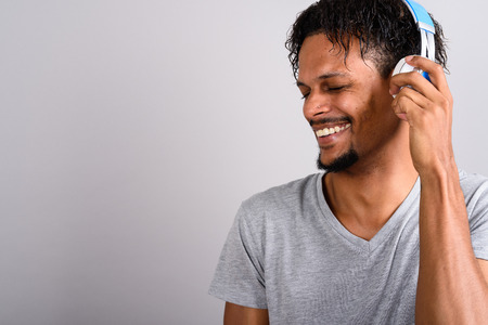 Young bearded handsome African man listening to music against grの写真素材