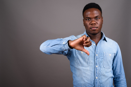Young African man wearing denim shirt against gray backgroundの写真素材