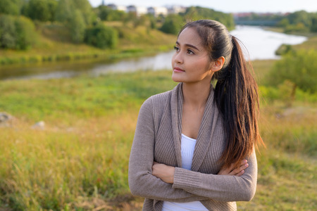 Young thoughtful Asian woman against relaxing view of nature