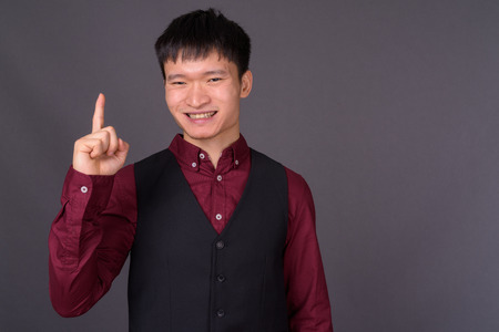 Portrait of young Chinese businessman against gray background