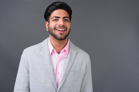 Young handsome Indian businessman against gray backgroundの写真素材