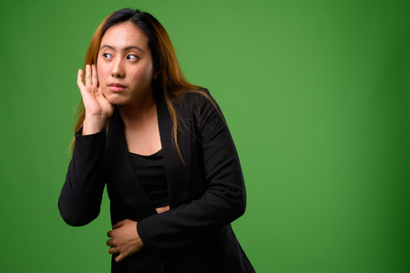 Portrait of young Asian businesswoman against green backgroundの写真素材