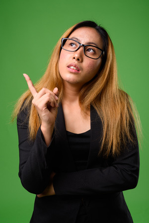 Portrait of young Asian businesswoman against green backgroundの写真素材