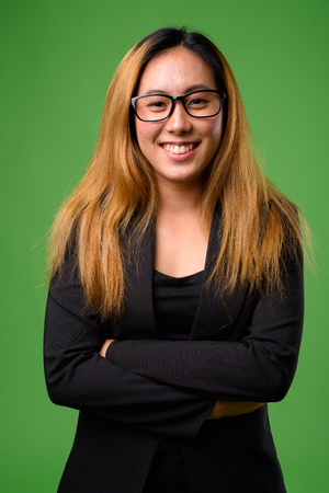 Portrait of young Asian businesswoman against green backgroundの写真素材