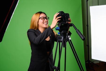 Portrait of young Asian businesswoman against green background