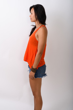 Profile view of young Asian woman standing against white backgroの写真素材