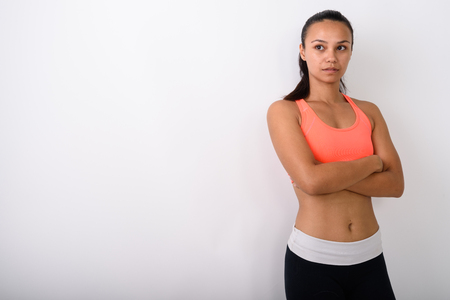 Studio shot of young Asian woman thinking with arms crossed readの写真素材
