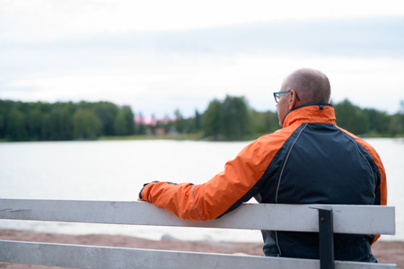 Senior Man Sitting And Relaxing By The Lakeの写真素材