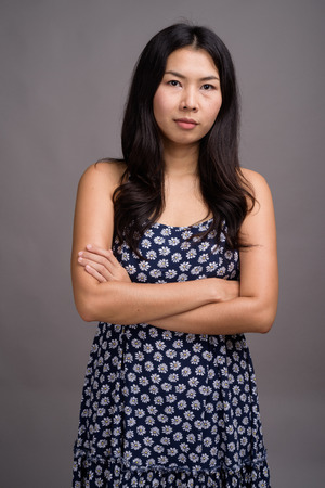 Asian woman wearing blue dress against gray backgroundの写真素材