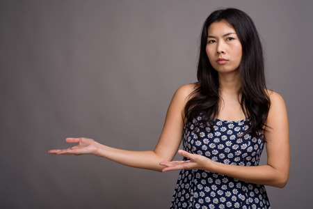Asian woman wearing blue dress against gray backgroundの写真素材
