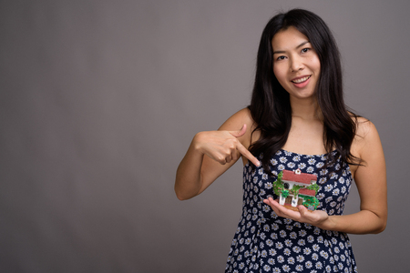 Asian woman wearing blue dress against gray backgroundの写真素材
