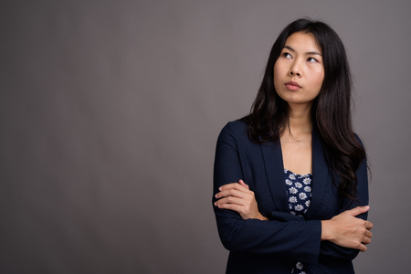 Asian woman wearing blue dress and cardigan sweater against grayの写真素材